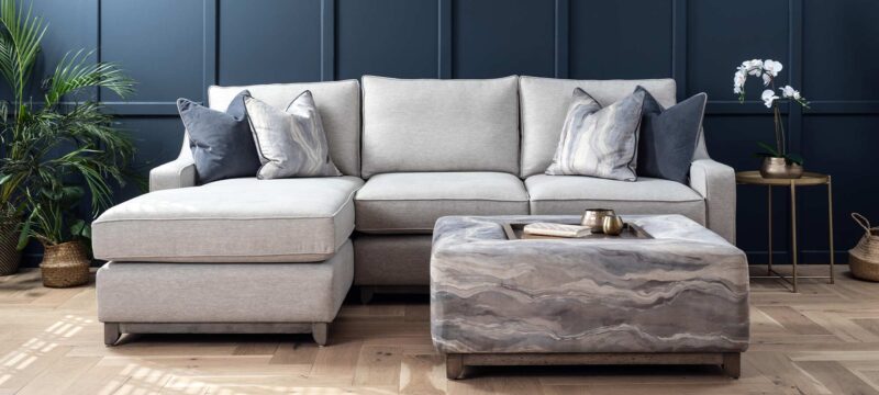 Gatsby chaise end sofa with ski arm and a wood plinth finished in a grey wash. Silver fabric with blue scatter cushions