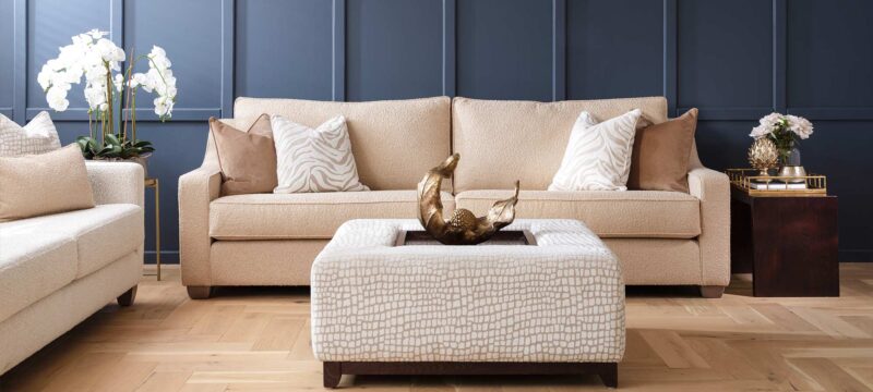 Hadley sofa with a ski arm and a contemporary wood foot. Upholstered in a cream fabric with nude coloured cushions