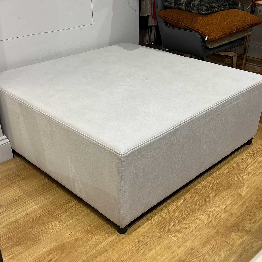 large square footstool in a cream fabric