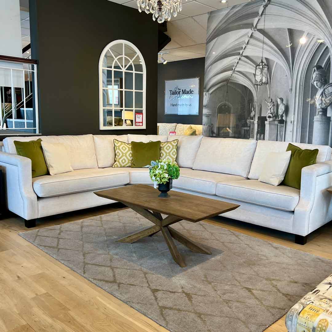 Plaza corner sofa. This corne sofa is Elegant and refined. Covered in easy clearn white fabric and enhanced with green scatter cushions.